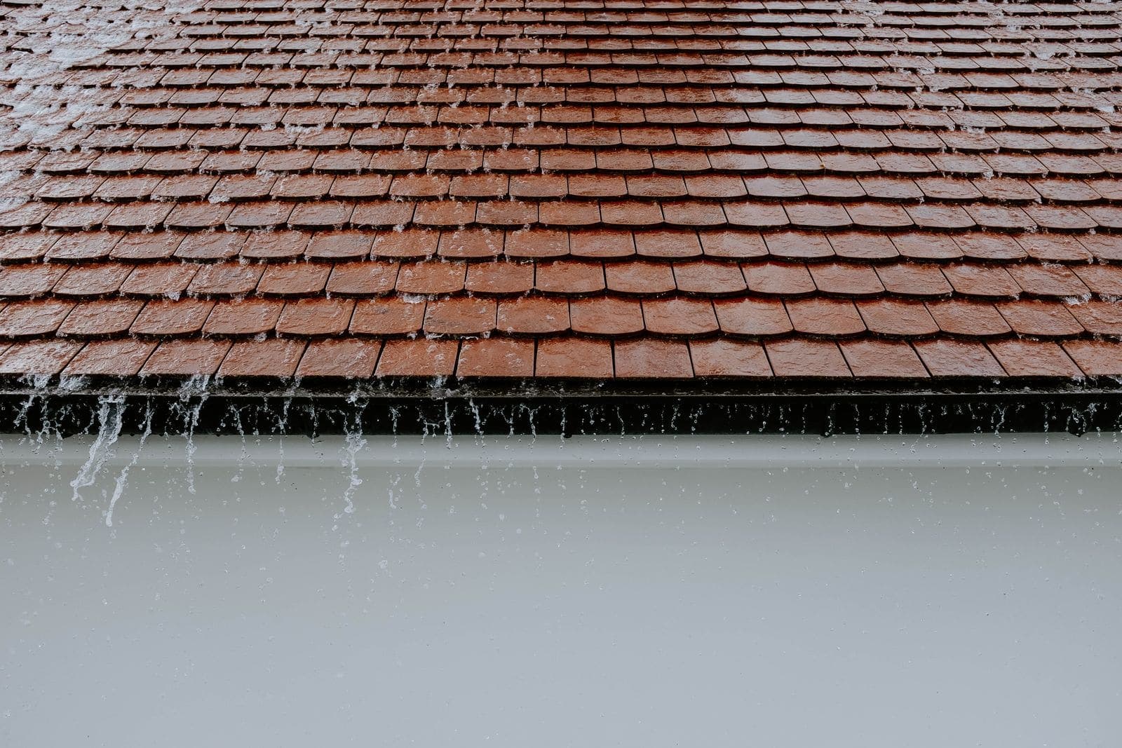 Rain pouring off the edge of a tiled roof
