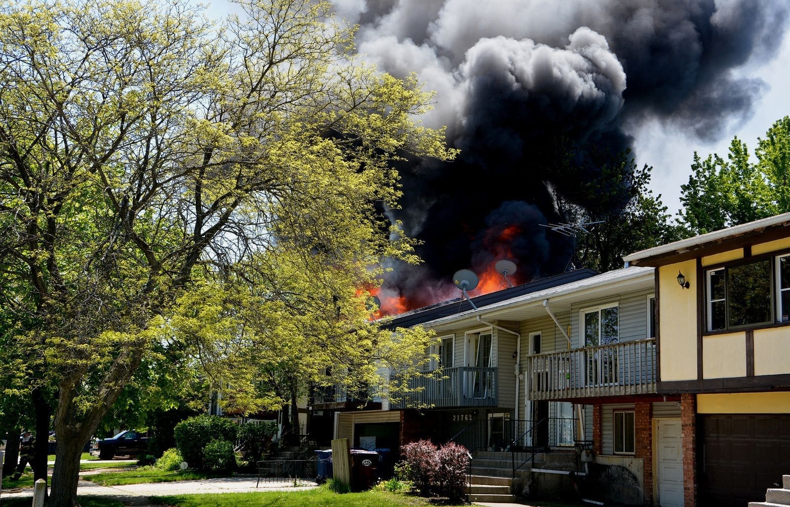 Black smoke rising from a house fire in a suburban neighborhood
